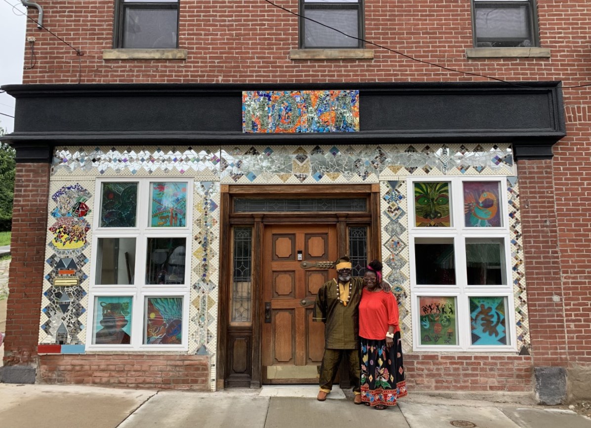 Studio owners standing in front of their new facade embellished with their mosaic design