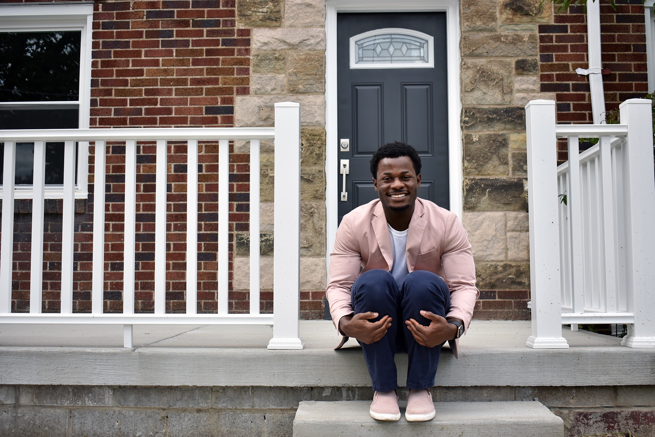 New homeowner Emerald Huggins proudly sits in front of his home