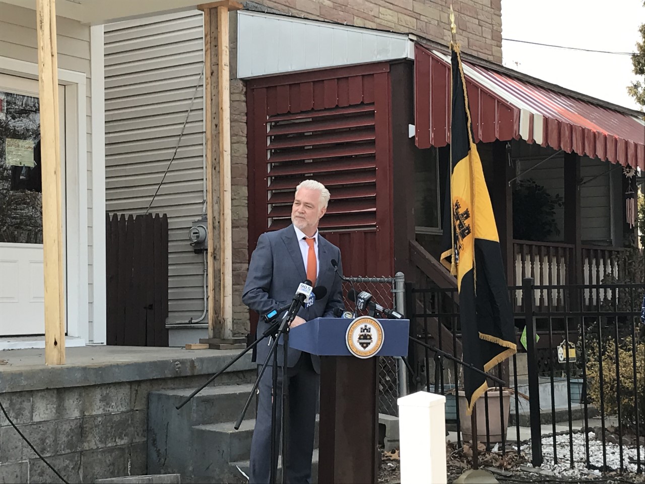 URA's Executive Director Greg Flisram gives remarks at a podium in front of a newly constructed home