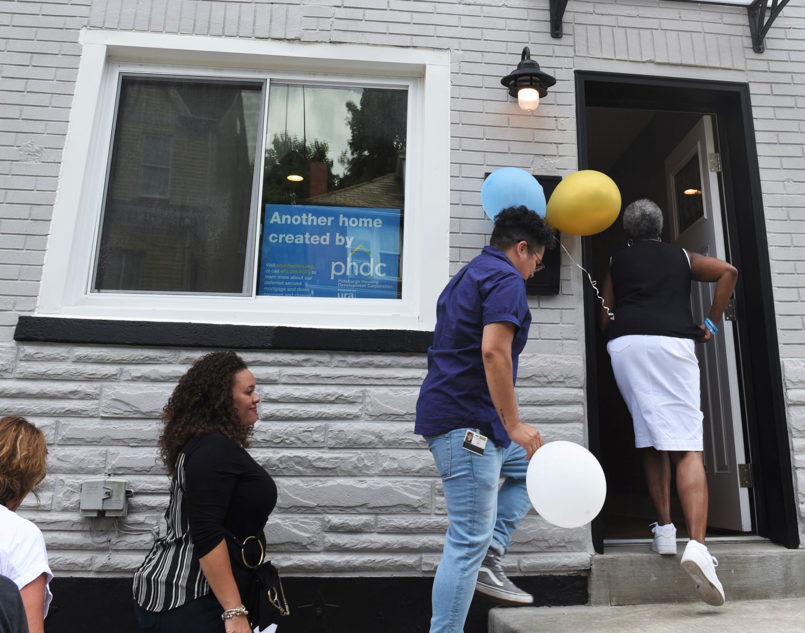People file into a recently rehabbed home with balloons placed next to the door