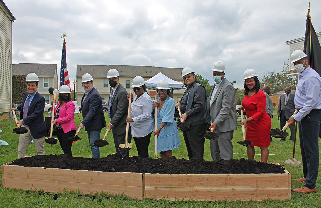 A group of elected officials and project partners smile and hold shovels during a shovel ceremony