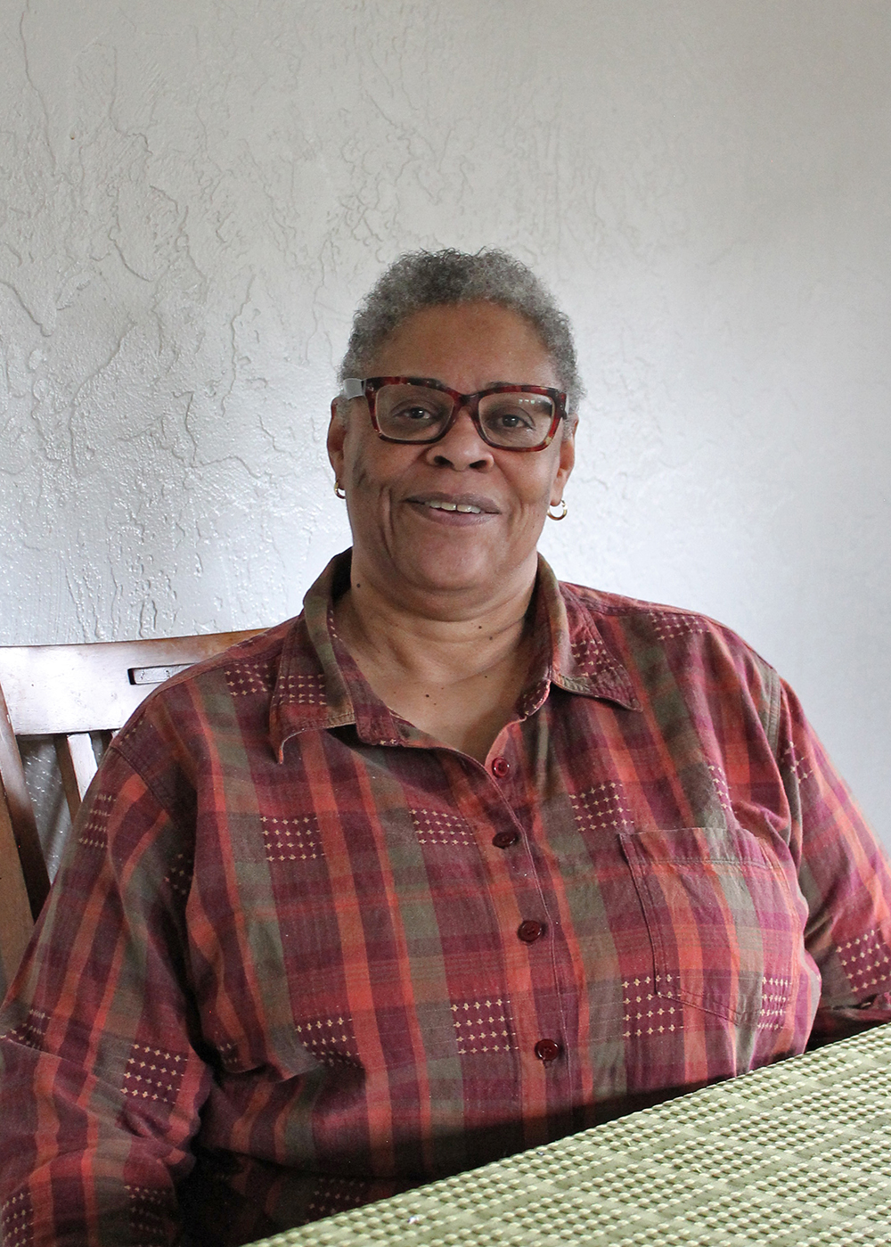 Homeowner Assistant Program client and Carrick homeowner Shirley Roberts sits at her dining room table and smiles.
